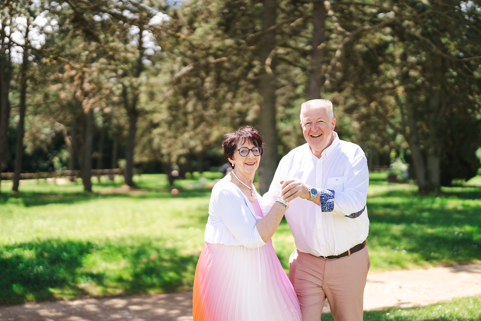 Un couple partage un moment complice et joyeux lors d’une séance photo famille en extérieur, dans un parc verdoyant des Vosges, sous une lumière naturelle d’été.
