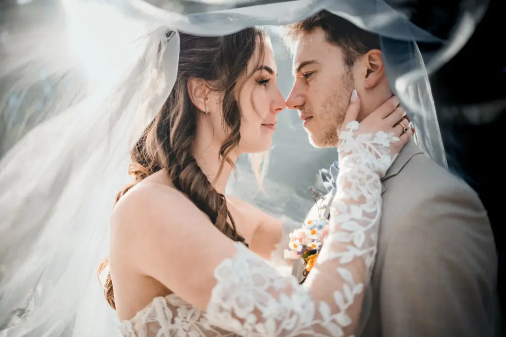 Mariés échangeant un regard intime sous le voile au Domaine du Feyel dans les Vosges