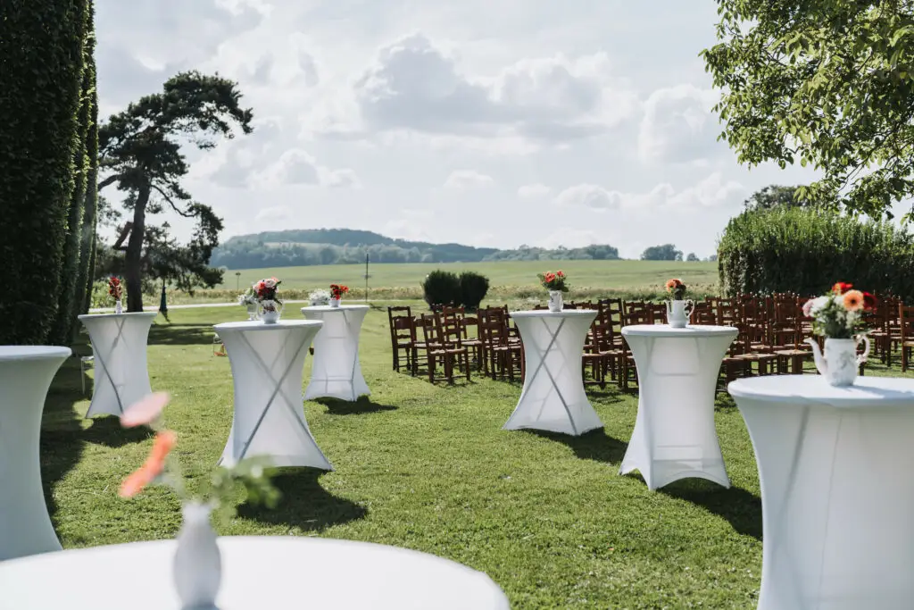 Installation de cérémonie laïque en plein air aux Templiers de Xugney dans les Vosges, tables hautes et chaises en bois face à la campagne