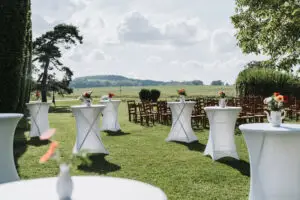 Installation de cérémonie laïque en plein air aux Templiers de Xugney dans les Vosges, tables hautes et chaises en bois face à la campagne
